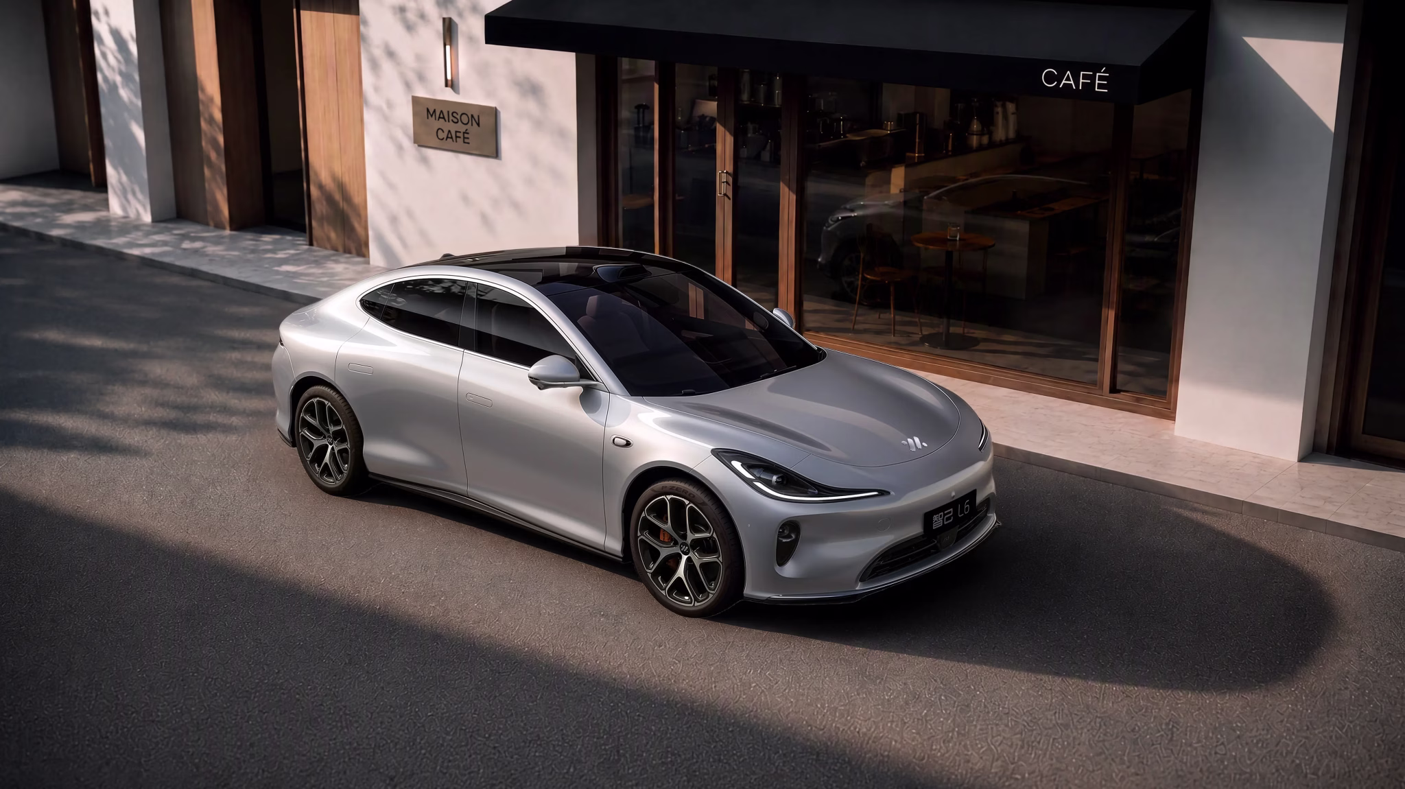 Silver 2026 IM L6 electric sedan outside a café, front three-quarter view